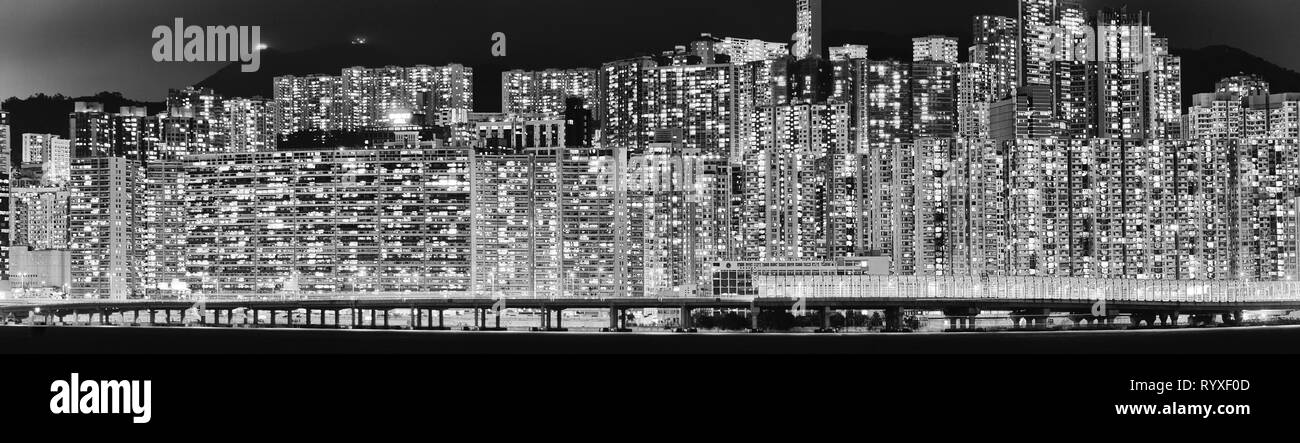 Brightly illuminated windows of endless wall of living houses and hotel accommodation in Hong Kong city on shores of Victoria harbour at night in wide Stock Photo