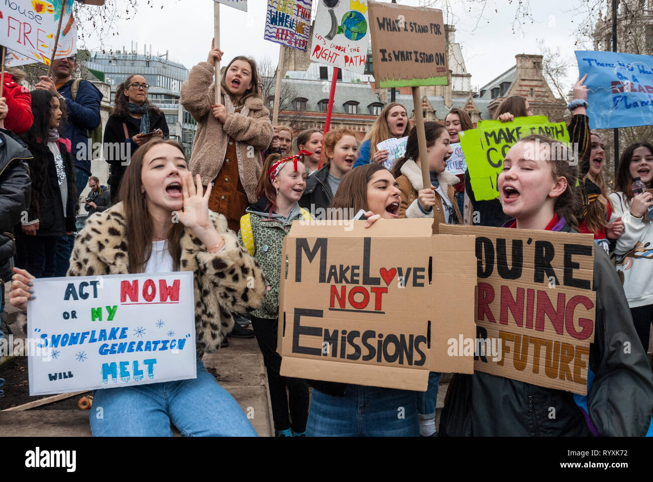 London, UK. 15th March, 2019. School students campaigning against climate change gather outside Parliament, London with colourful home made banners. Credit: Maggie sully/Alamy Live News.London, UK. School children on strike, part of the 'FridaysforFuture' protest against climate change gathering outside Parliament, London. Girls shouting slogans about planet justice and global warming carrying colourful homemade placards 'Act now or my snowflake generation will melt', 'Make love not emissions' and 'Your burning our future'. Stock Photo