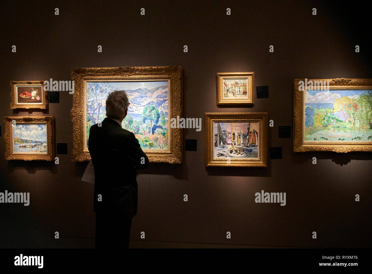 A visitor observes the paintings exhibited in one of the galleries participating in TEFAF. TEFAF (The European Fine Art Fair), one of the most famous art, antiques and design fairs in the world, is held once again this year. Every year, Maastricht hosts an event that brings together 275 galleries some twenty countries, about 30.000 exhibited art objects and has more than 75,000 attendees each year. Stock Photo