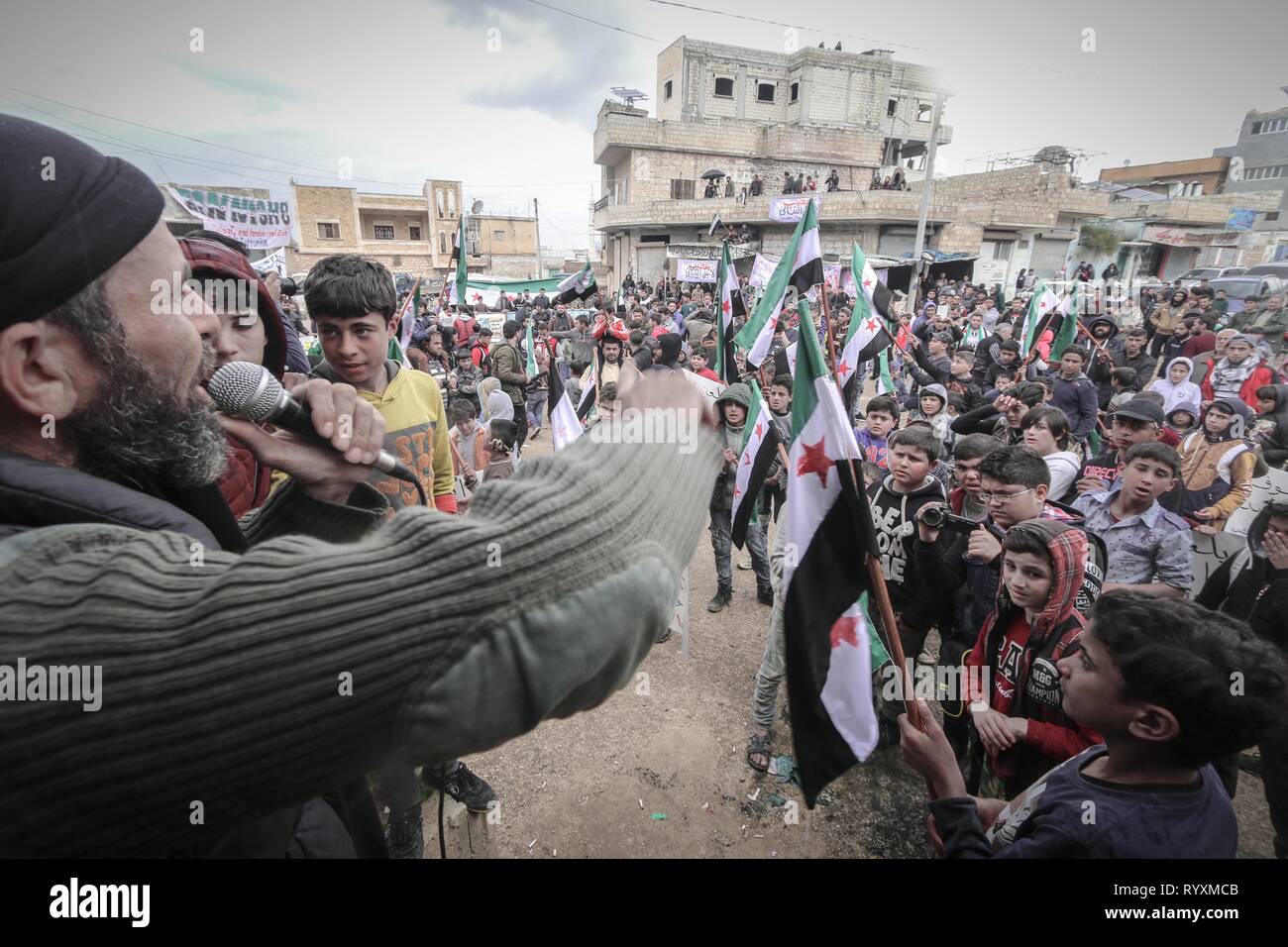 Benesh, Idleb, Syria. 15th Mar, 2019. A Syrian seen speaking to the participants holding opposition flags during the celebration.Syrians in the town of Bensh, which lies east of Idlib and controlled by the opposition, celebrated the eighth anniversary of the uprising against the rule of President Bashar al-Assad. Credit: Mohamad Saeed/SOPA Images/ZUMA Wire/Alamy Live News Stock Photo
