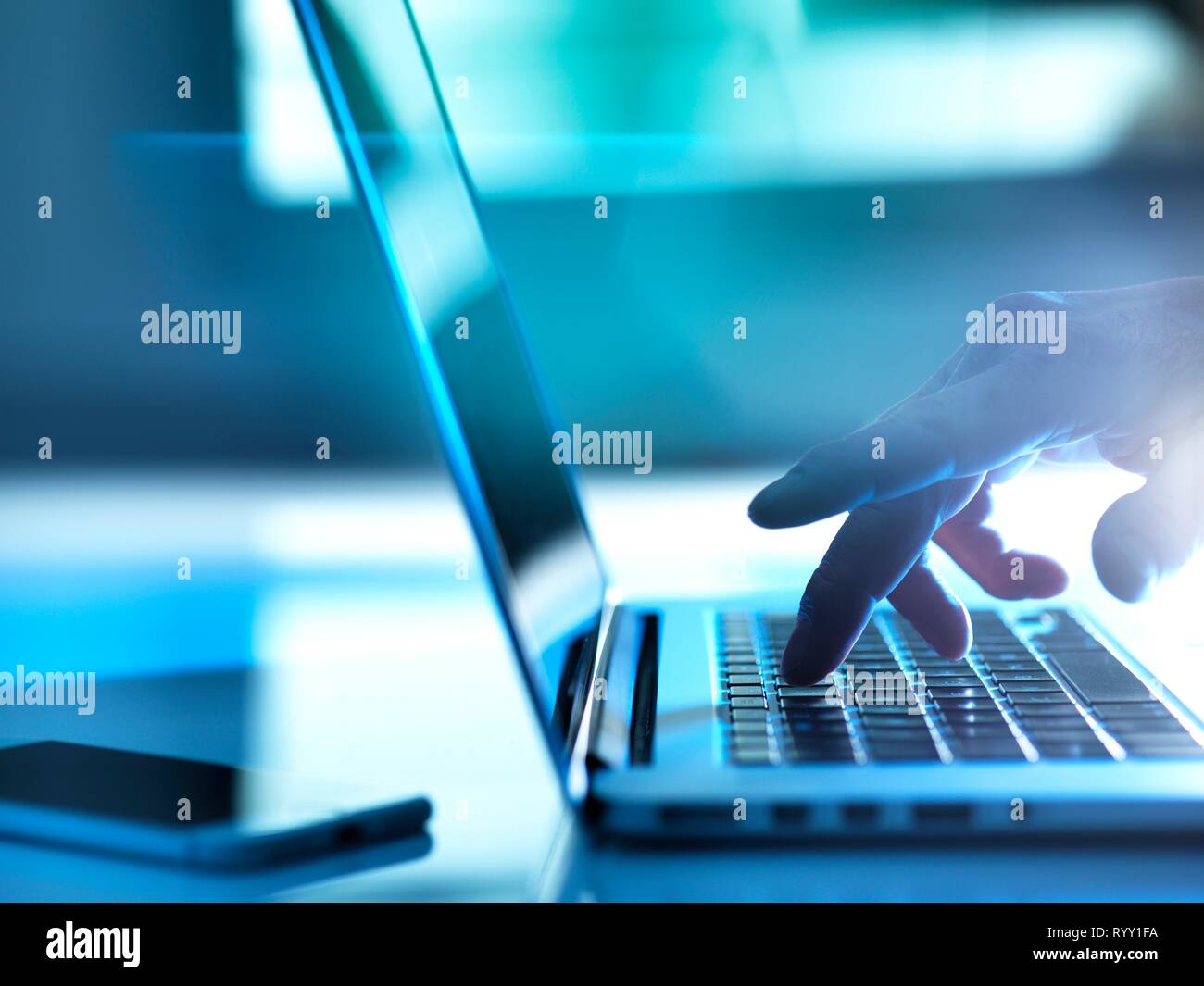 Man typing on a laptop computer at his desk. Stock Photo