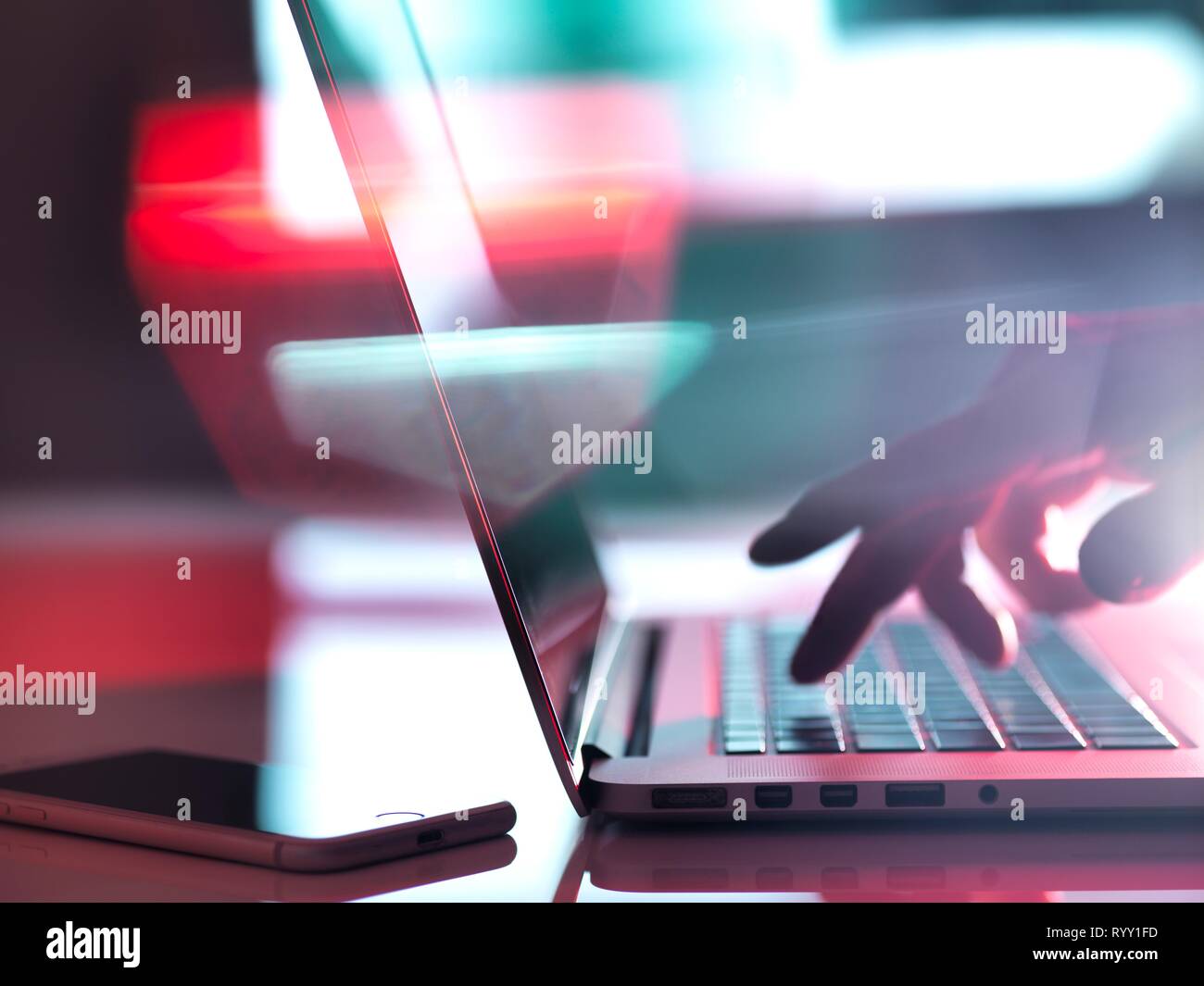 Man typing on a laptop computer at his desk. Stock Photo