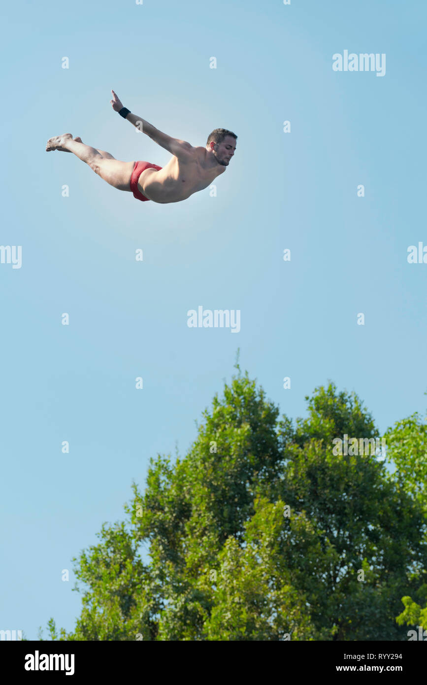 Swan dive from high platform. Stock Photo
