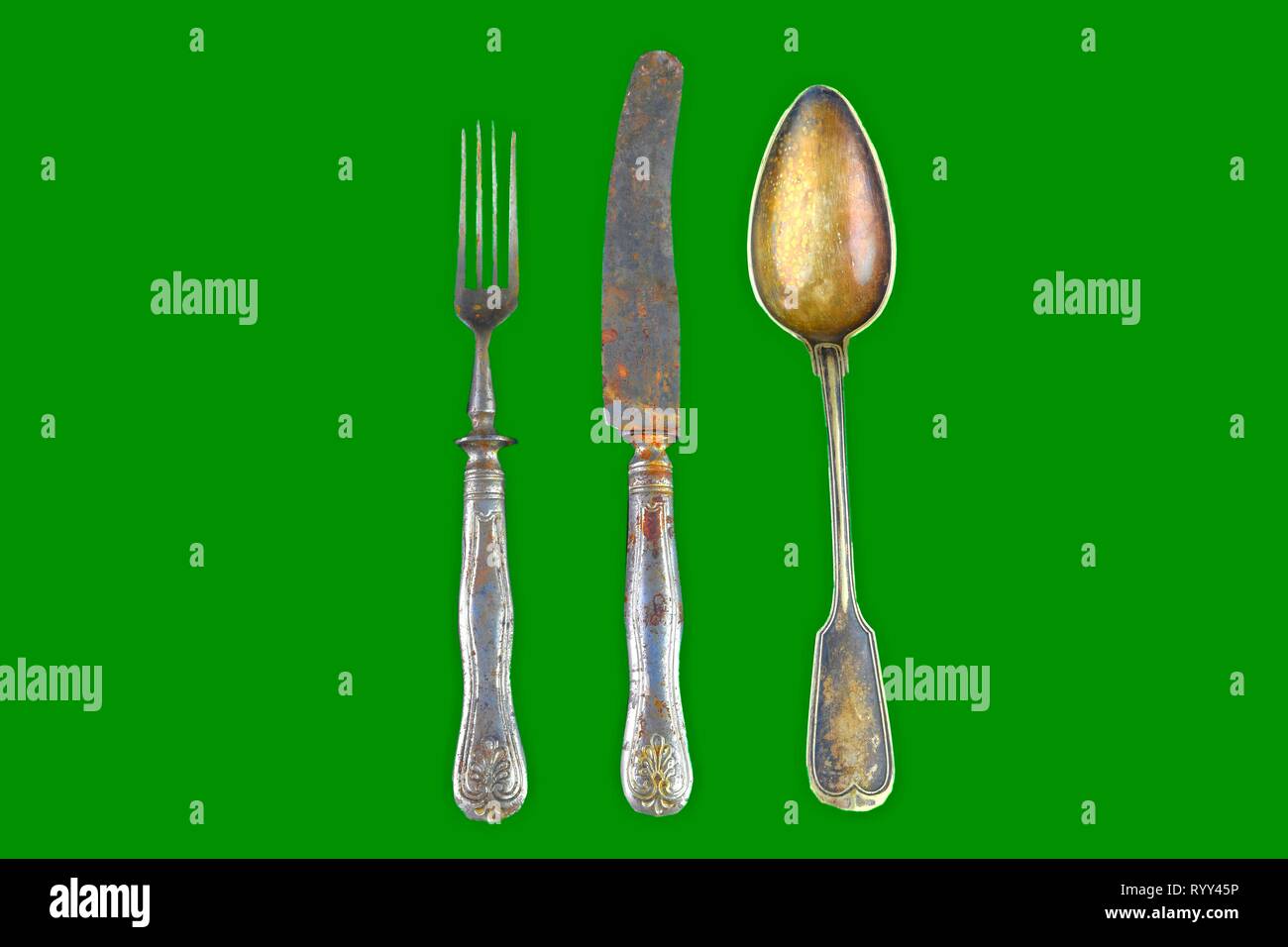 Vintage cutlery on a green background. Top view. Crazy concept for culinary and modern life. Contrast between shabby cutlery and excellent modern colo Stock Photo