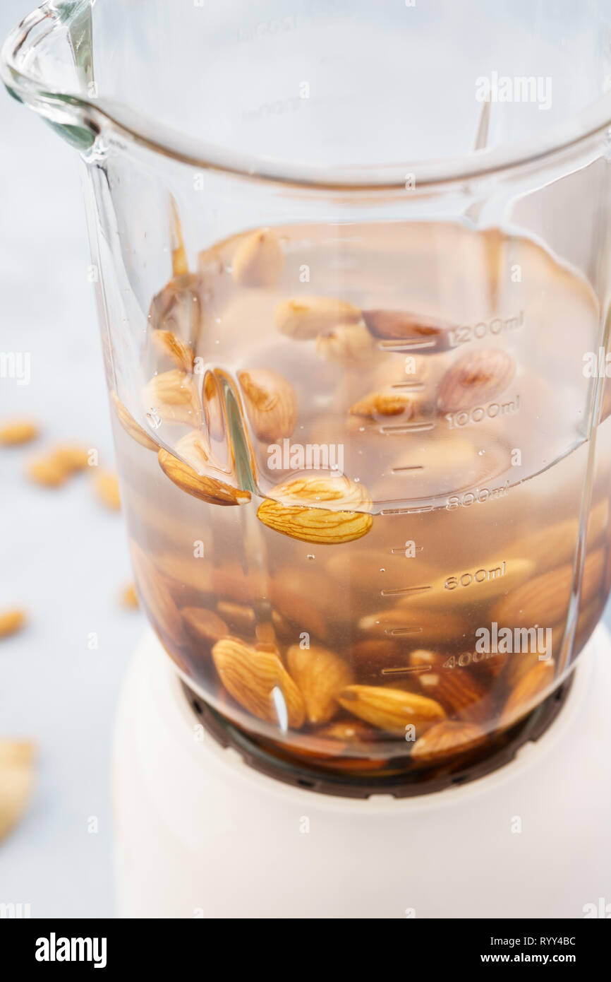 Blender and almonds soaked in water. Making healthy vegan milk. Stock Photo