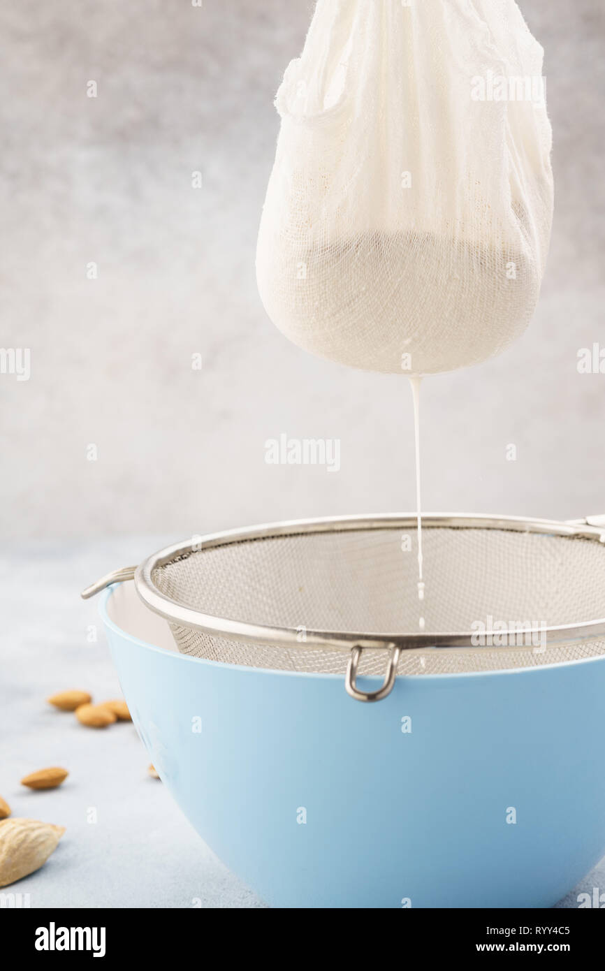 Homemade nut milk making process. Pouring milk into cloth. Step by step recipe. Stock Photo