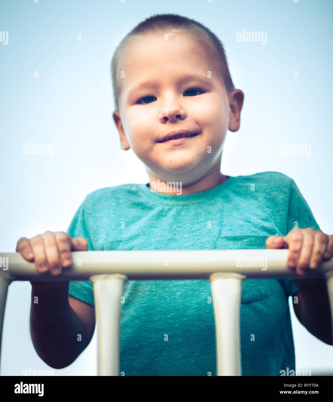 Little smiling boy playing on a slide. Outdoor activity Stock Photo
