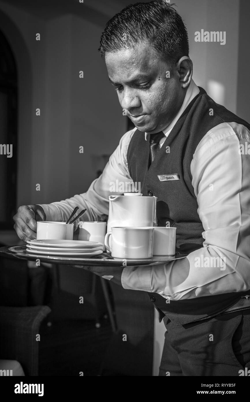 Suhith - A professional Waiter at the historic Galle Face hotel in Colombo Sri Lanka, dispensing tea to the guests on the seafront patio. Stock Photo