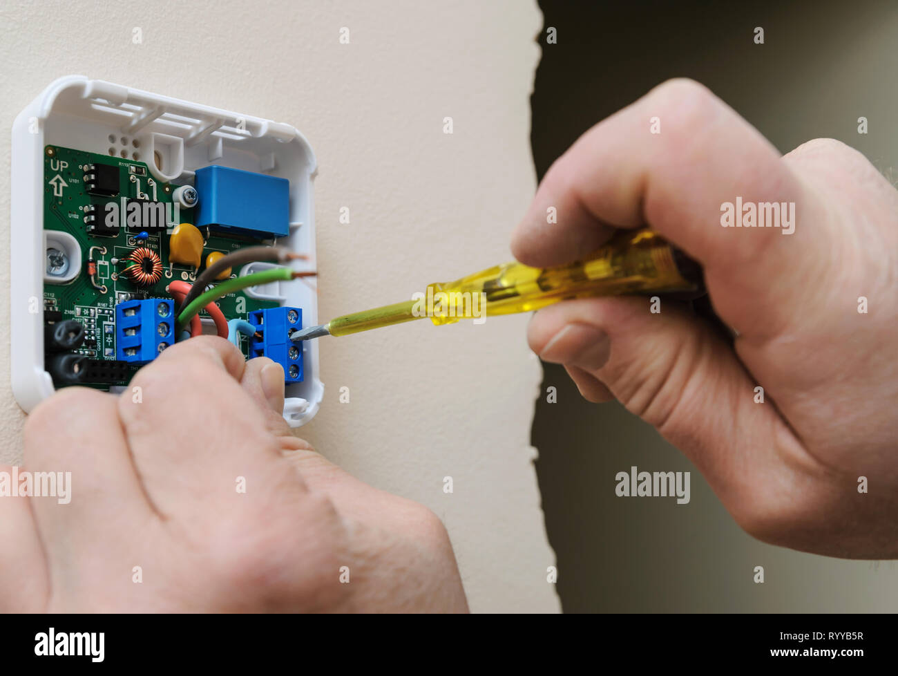 Installing a programmable room thermostat. Man's hands fixing the wires