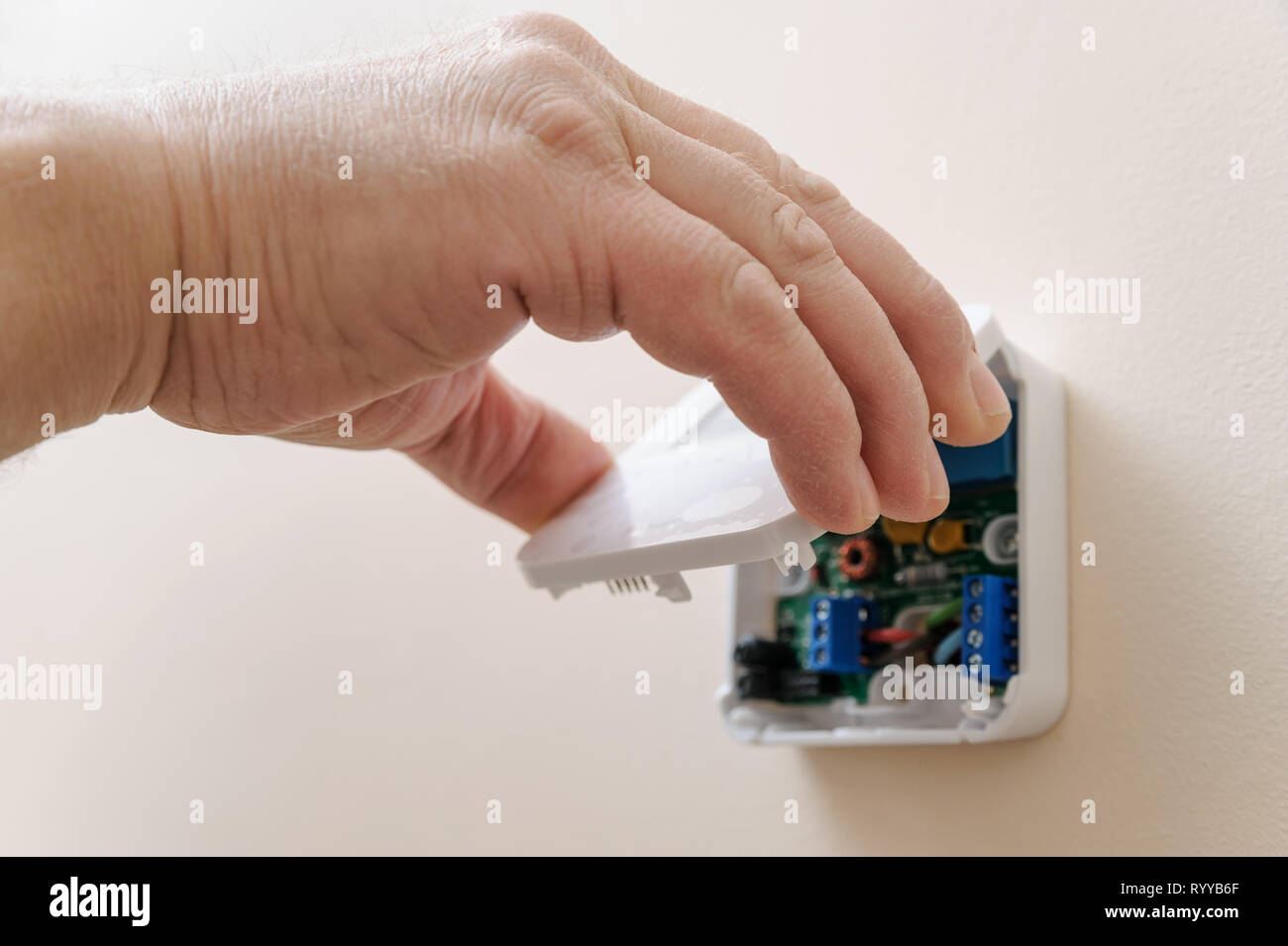 Installing a programmable room thermostat. Man's hand holding the lid