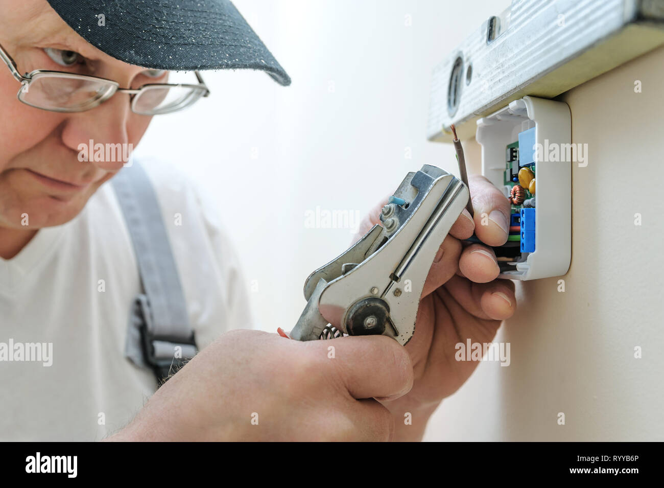 Installing a programmable room thermostat. Worker strips insulation of