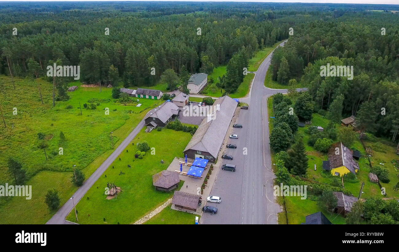 The aerial view of the parking area on the roadside with tall trees on the forest seen the intersections and cars passing by Stock Photo