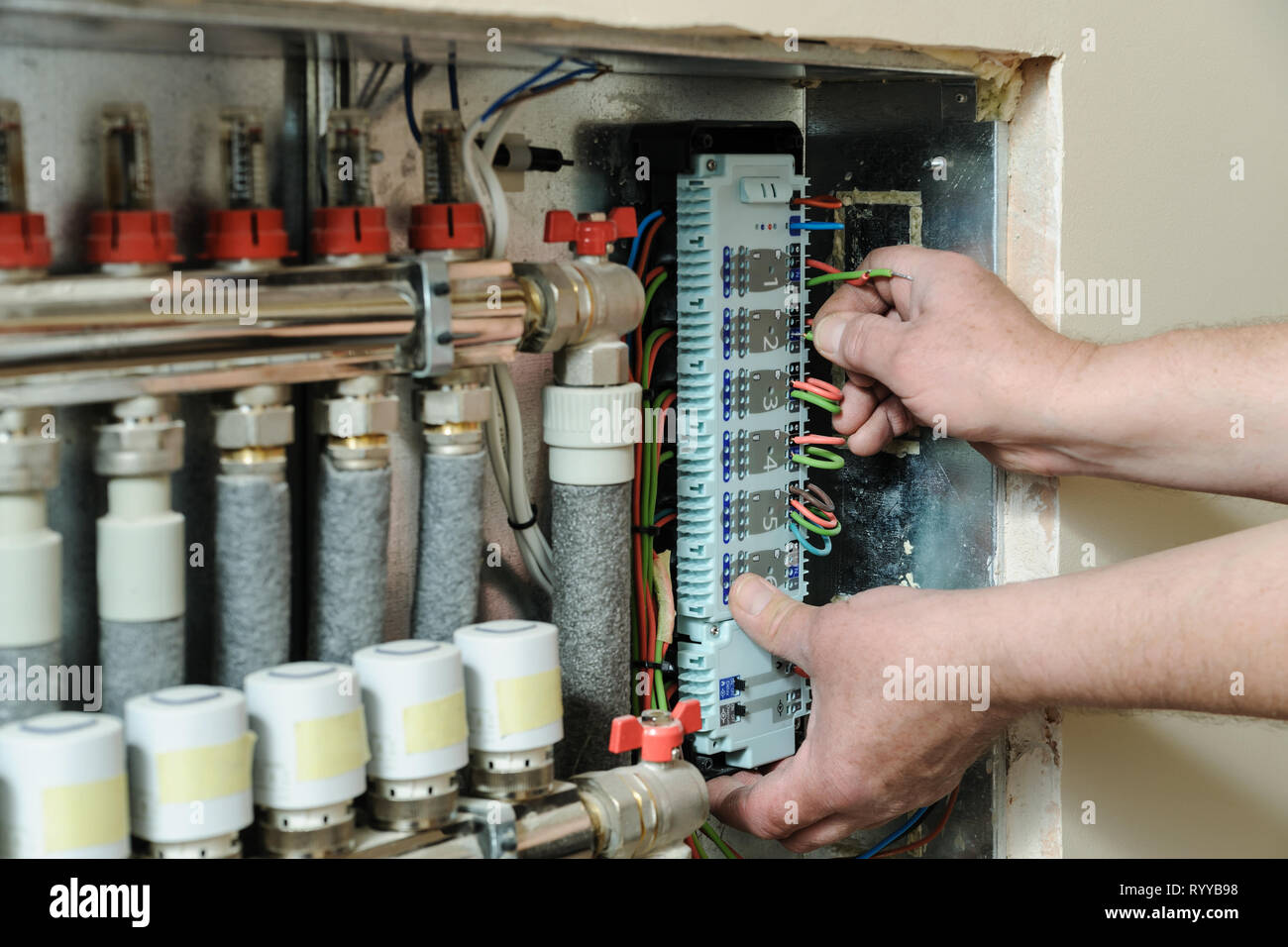 Electrician's hands are inserting wires in a switch for thermostats and servo drives valves in a