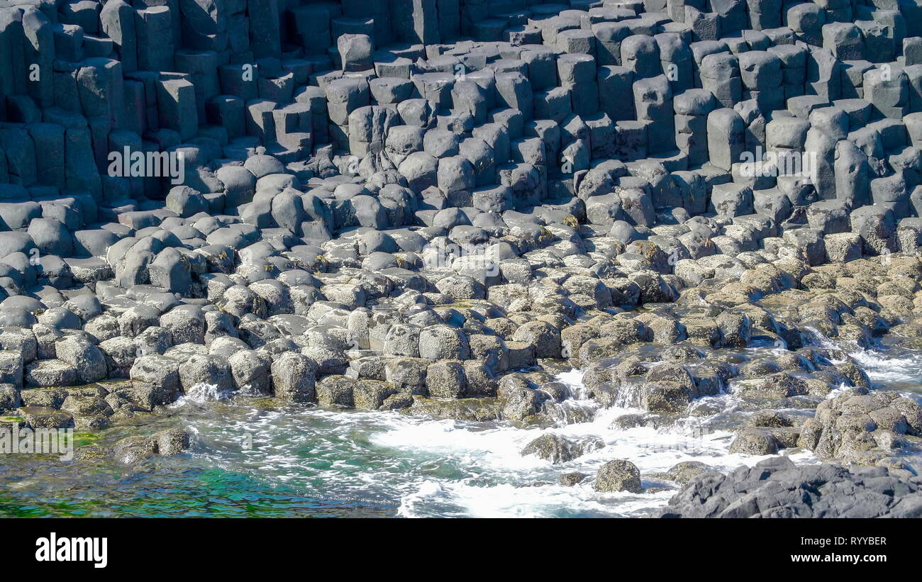 Rocks on the seashore in the Giants Causeway with the splash of waves coming from the sea Stock Photo