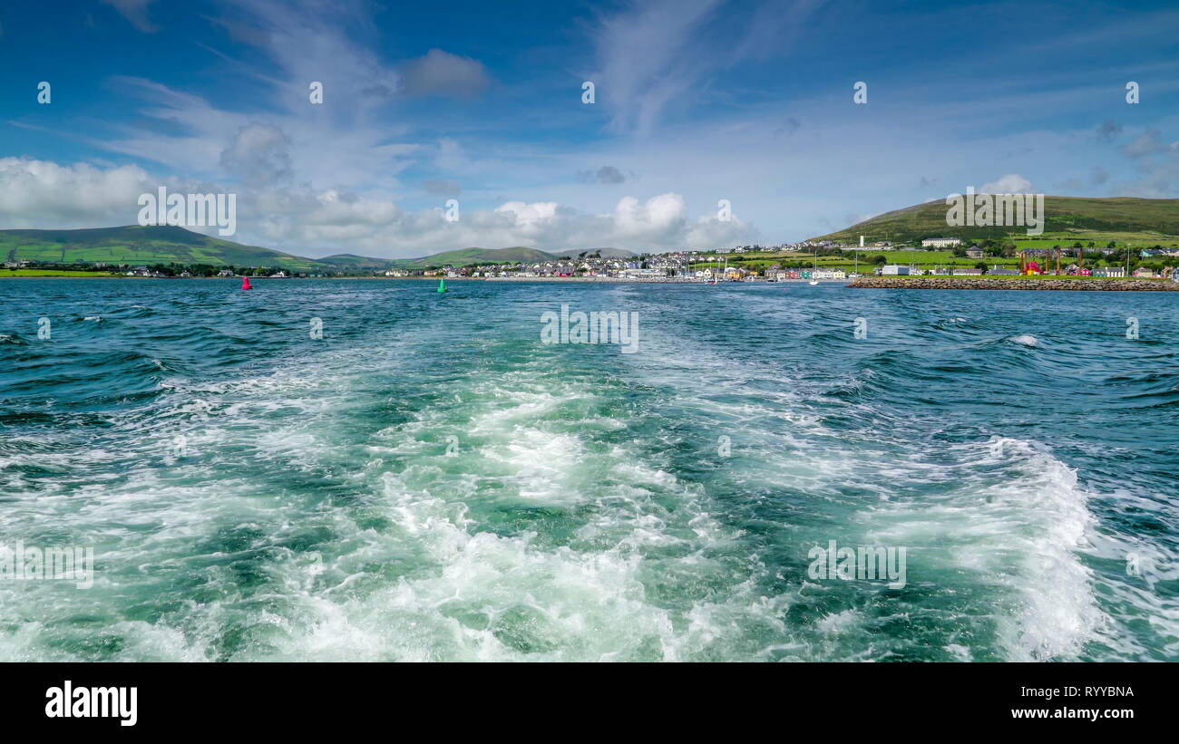 View of the Dingle village and the white bubbles from the ferry cruising the sea seeing the village in Ireland in far away Stock Photo