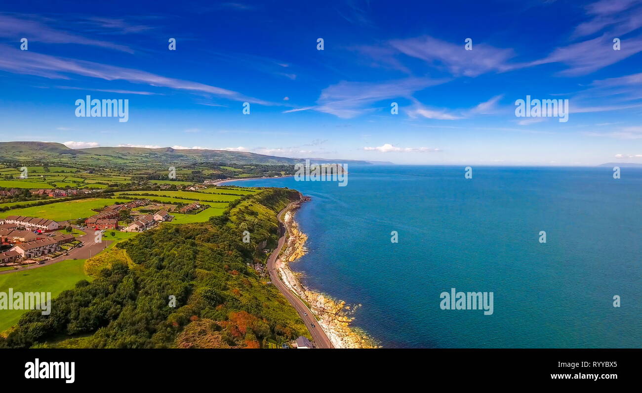 Aerial landscape shot of the coastal village of Cushendun found in the Northern Ireland with the big sea and the trees in the forest Stock Photo