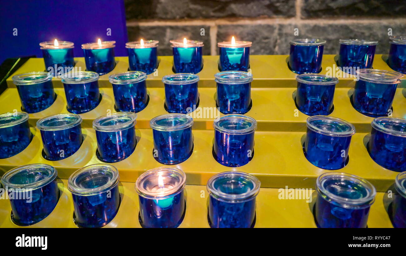 Blue candles on the candle holders inside the abbey the candles being lighted inside a church in Ireland Stock Photo