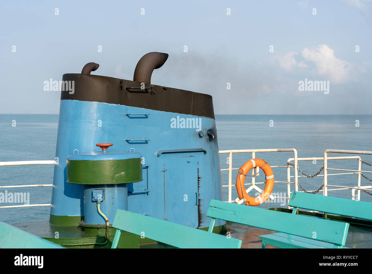 Smoke from ferry boat flue during sea with sunlight, sea water and blue