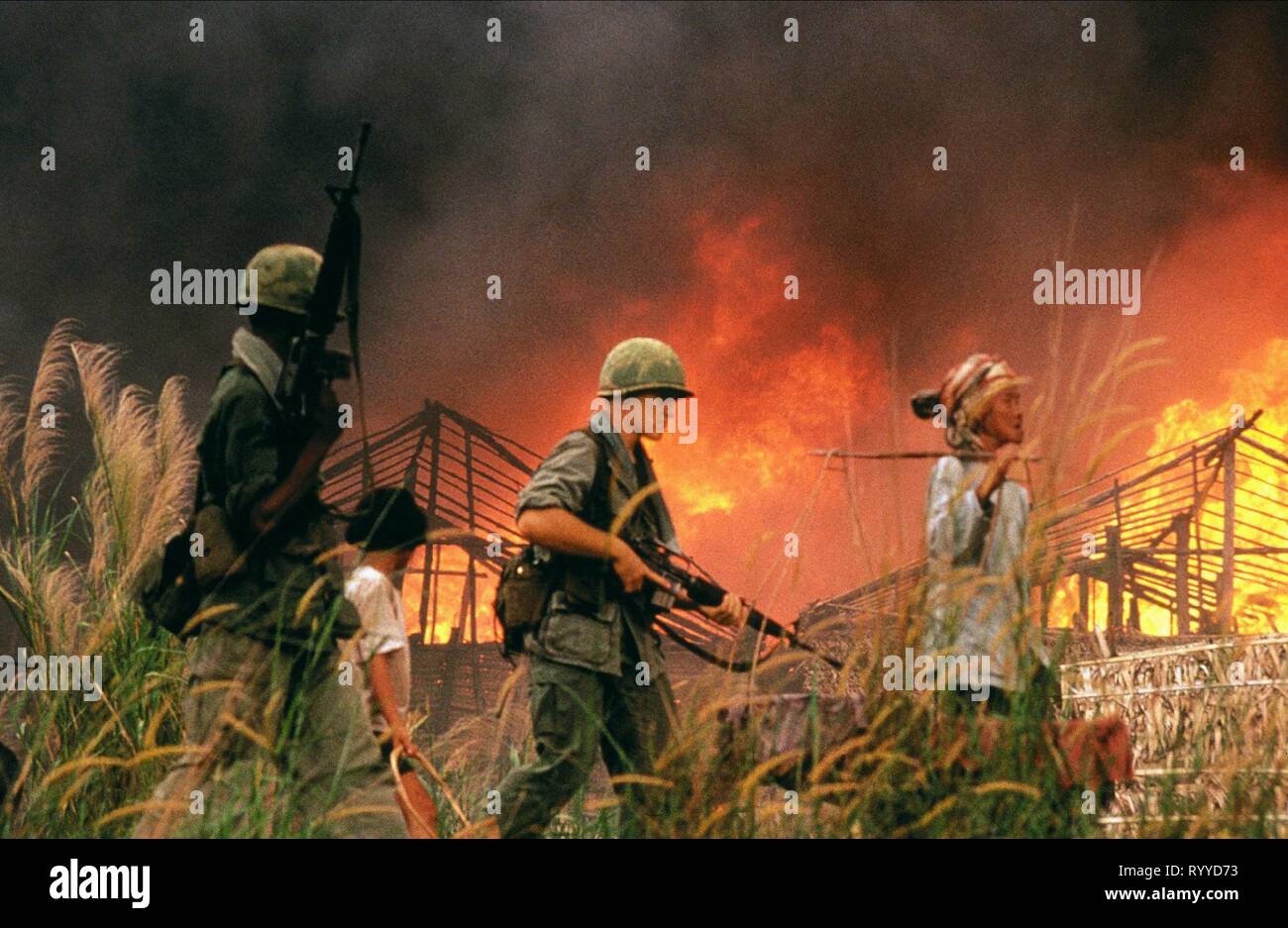 US SOLDIERS PASS BURNING HUTS, CASUALTIES OF WAR, 1989 Stock Photo