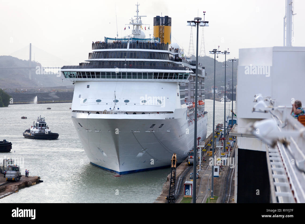 The cruise ship is being pulled by land transportation through narrow canal entrance (Panama). Stock Photo