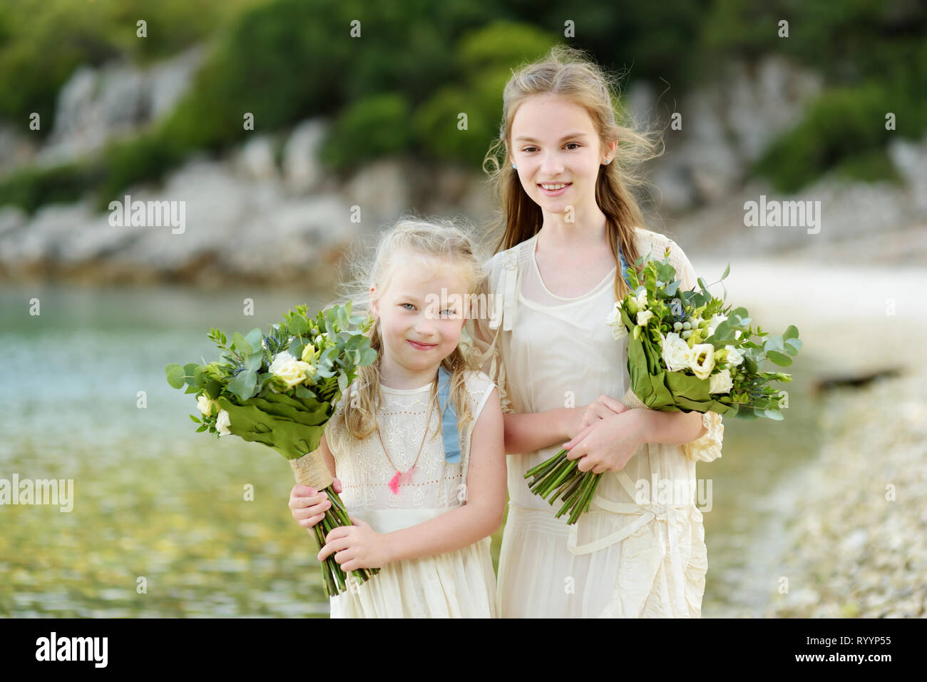 Two Adorable Young Bridesmaids Holding Beautiful Flower Bouquets