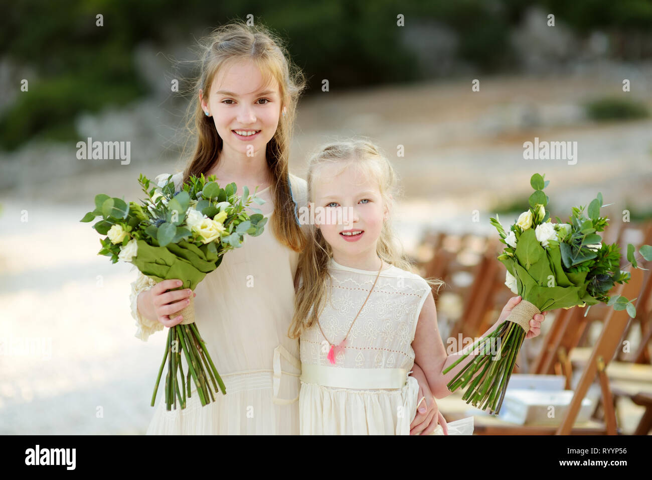 Two Adorable Young Bridesmaids Holding Beautiful Flower Bouquets