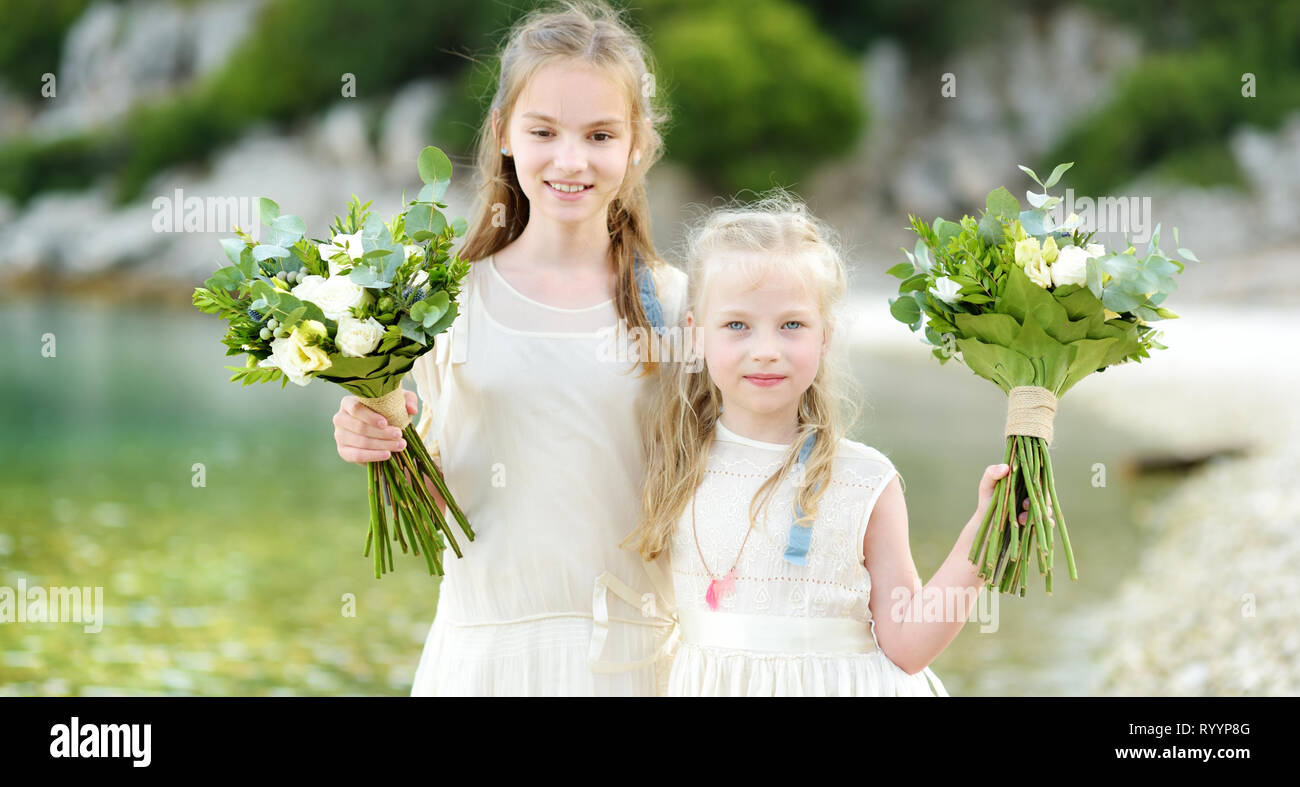 Two Adorable Young Bridesmaids Holding Beautiful Flower Bouquets