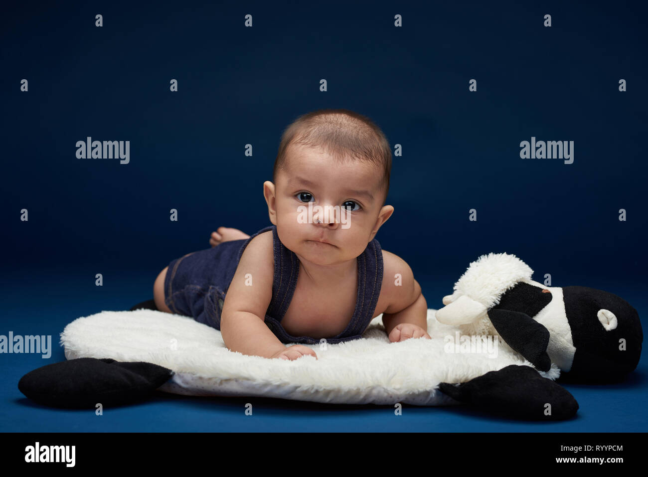 Small child lay on pillow in blue studio background. Kids theme Stock Photo  - Alamy