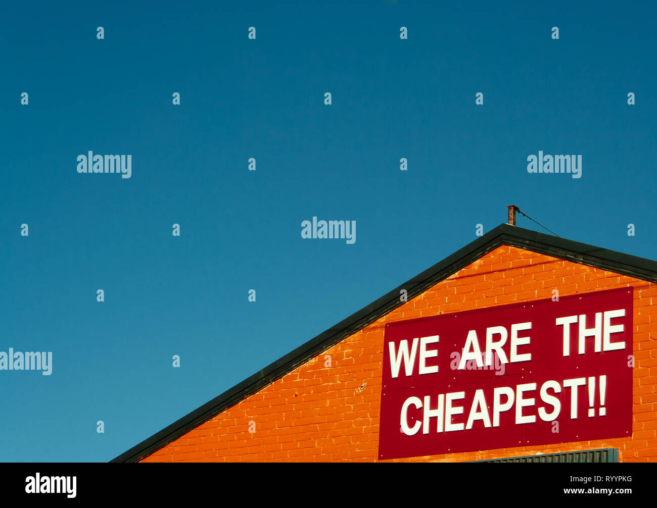 Discount prices sign on an orange warehouse against a clear sky Stock Photo