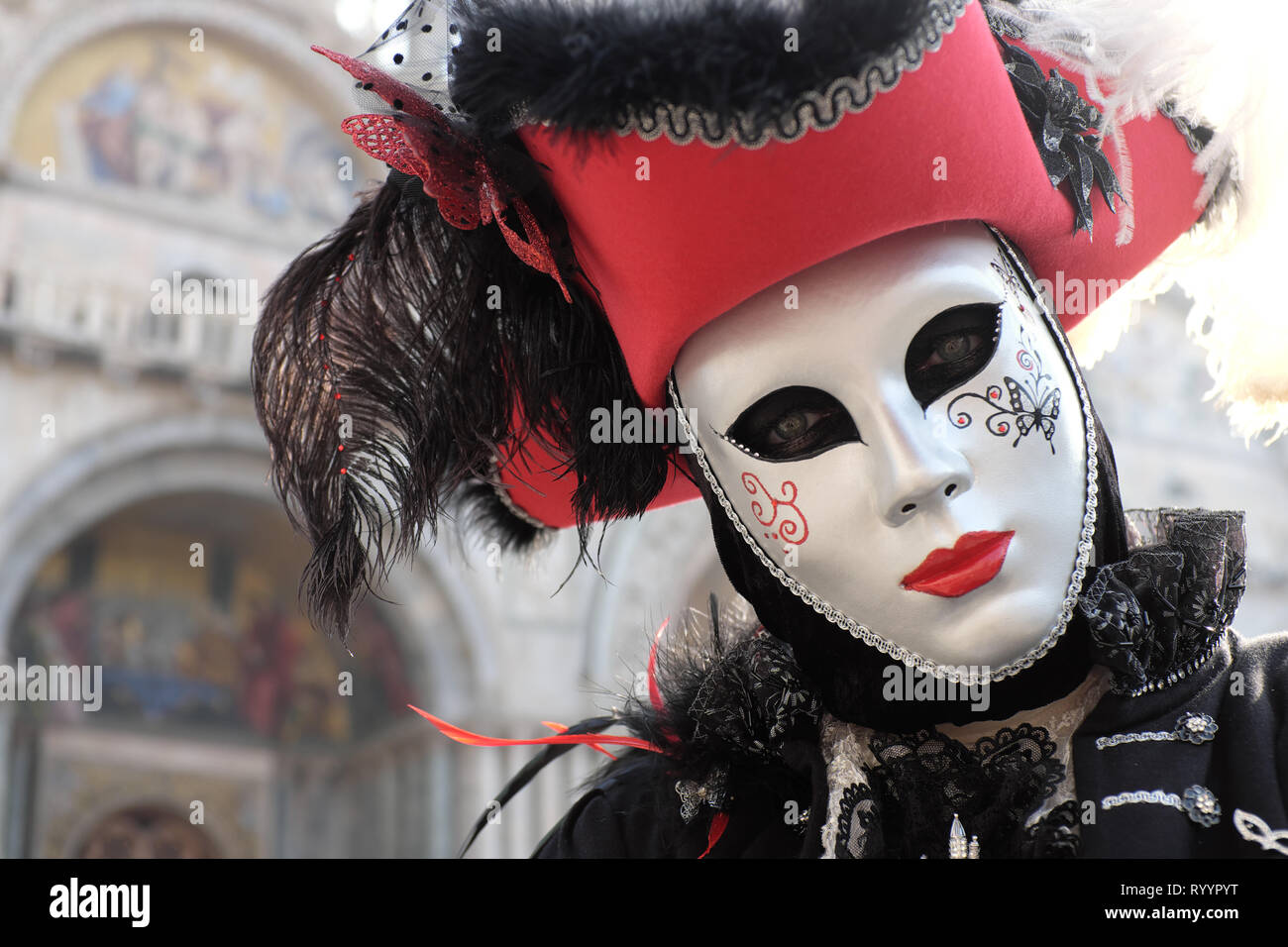 Man dressed in traditional mask and costume for Venice Carnival standing in Piazza San Marco in front of Saint Mark's Basilica, Venice, Veneto, Italy Stock Photo