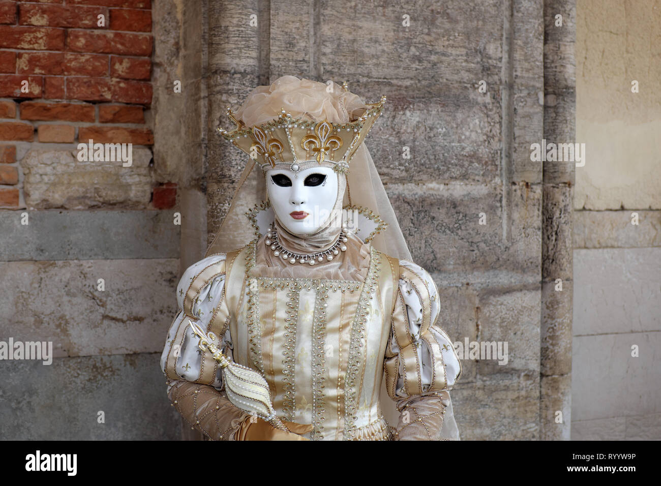 Woman dressed in traditional mask and costume for Venice Carnival standing at Doge’s Palace, Piazza San Marco, Venice, Veneto, Italy Stock Photo