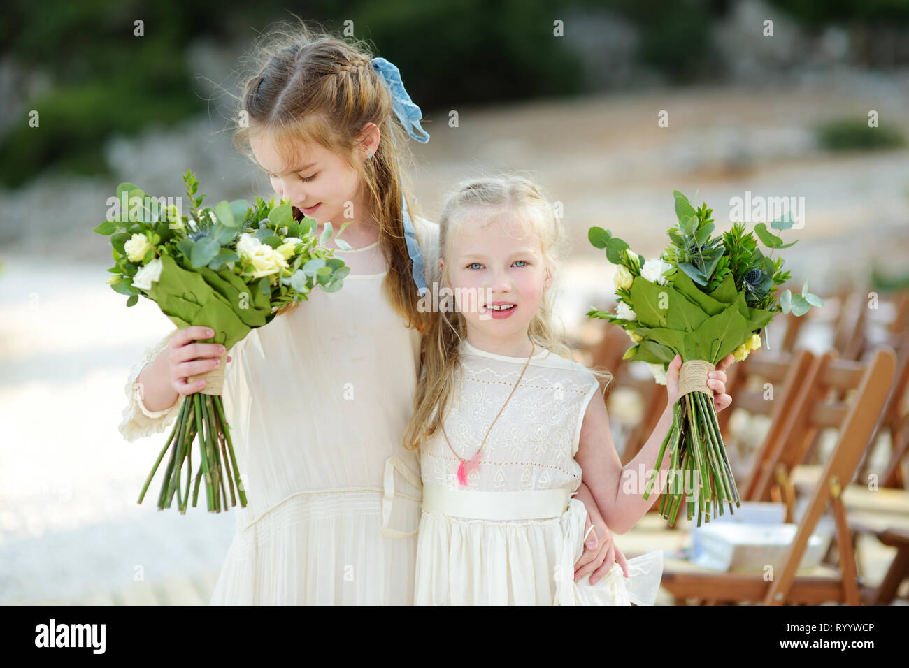 Two Adorable Young Bridesmaids Holding Beautiful Flower Bouquets