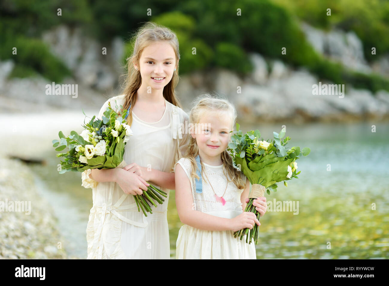 Two Adorable Young Bridesmaids Holding Beautiful Flower Bouquets