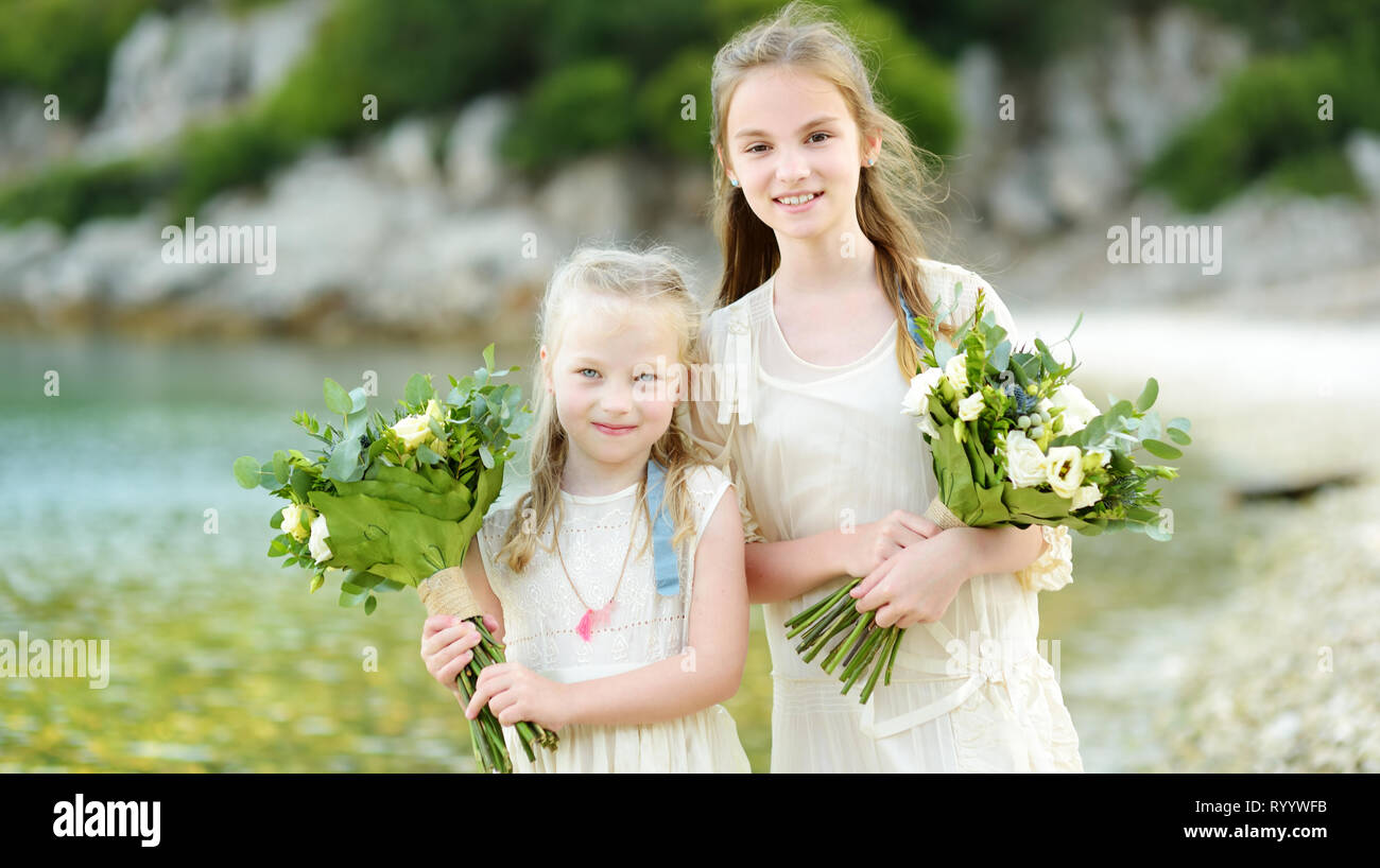 Two Adorable Young Bridesmaids Holding Beautiful Flower Bouquets