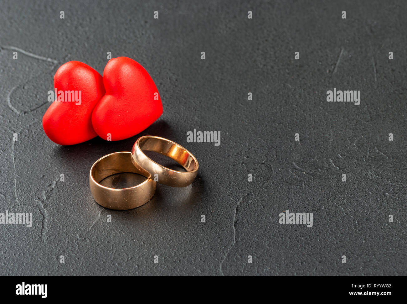 Gold engagement rings with two hearts on dark background Stock Photo - Alamy