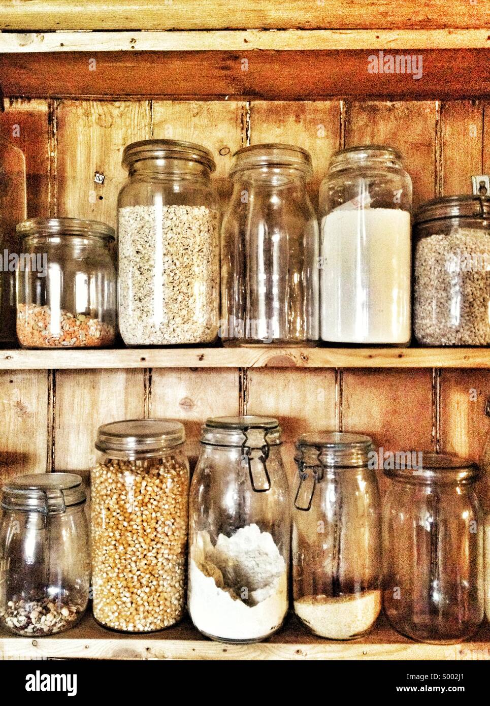 Old fashioned jars containing grains, pulses and flour in kitchen
