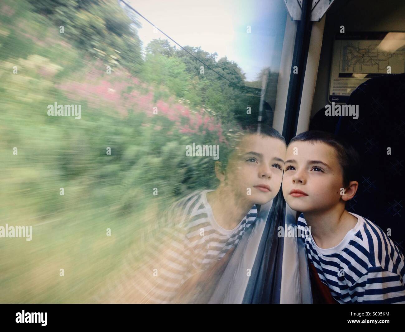 Young boy gazing out of train window Stock Photo