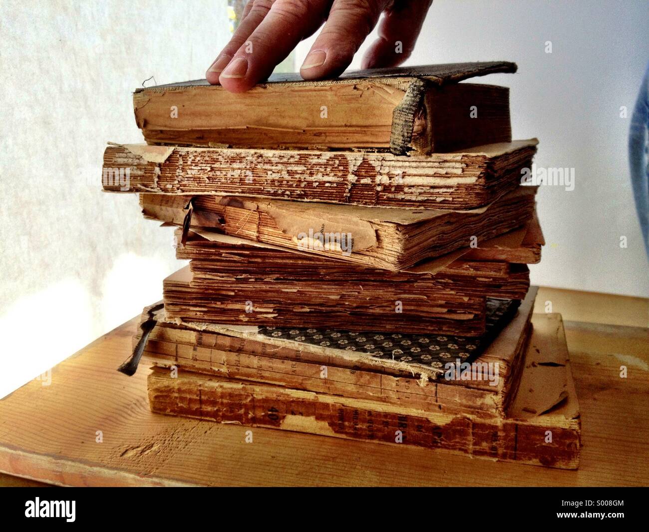 Hand on stack of old books - Smartphone Captured Stock Image