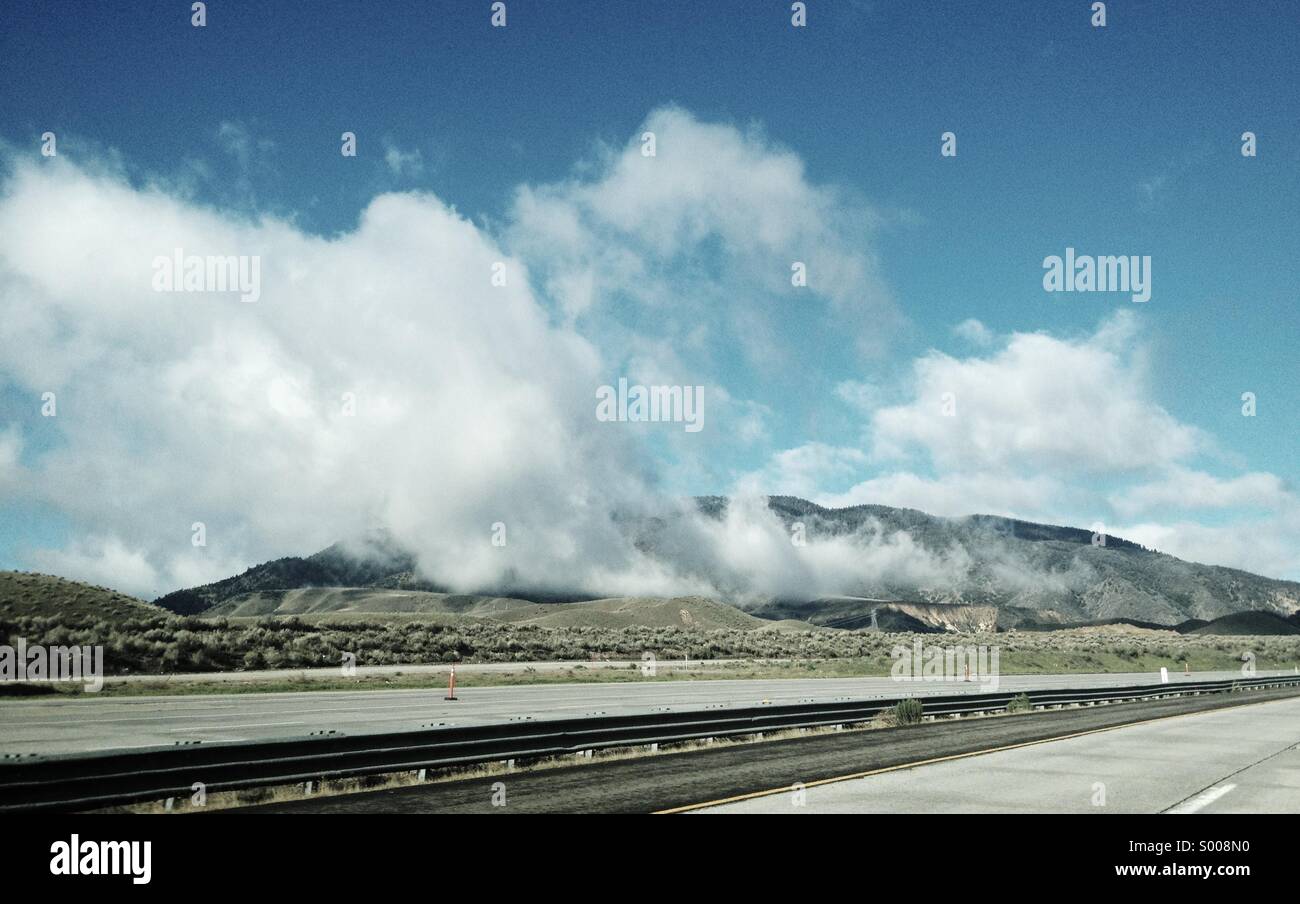 High up in the hills, a storm has passed and clouds drift over the open road. Stock Photo