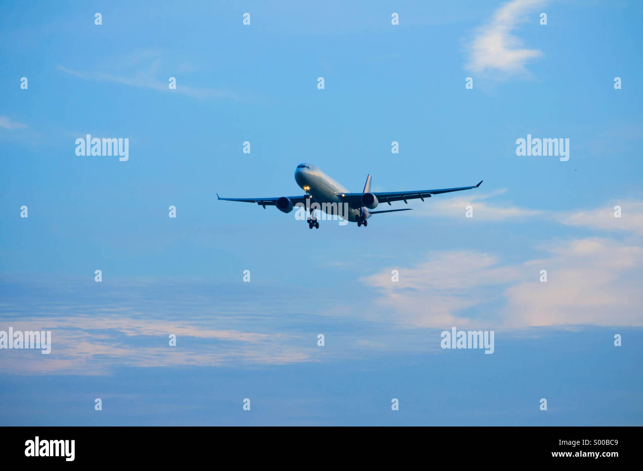 Landing airplane on blue sky background Stock Photo - Alamy