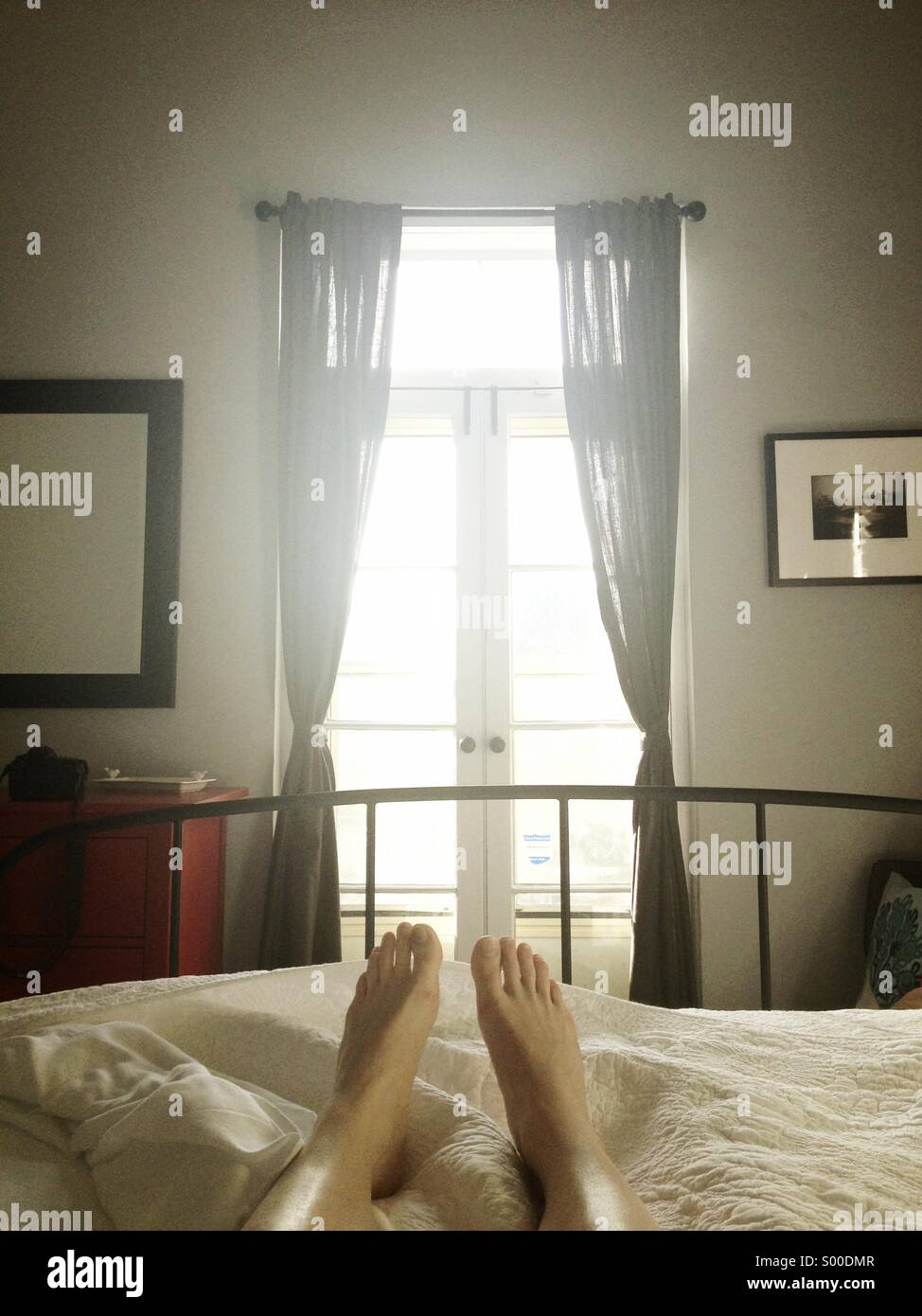 Woman in bed waking up to a sunny morning Stock Photo