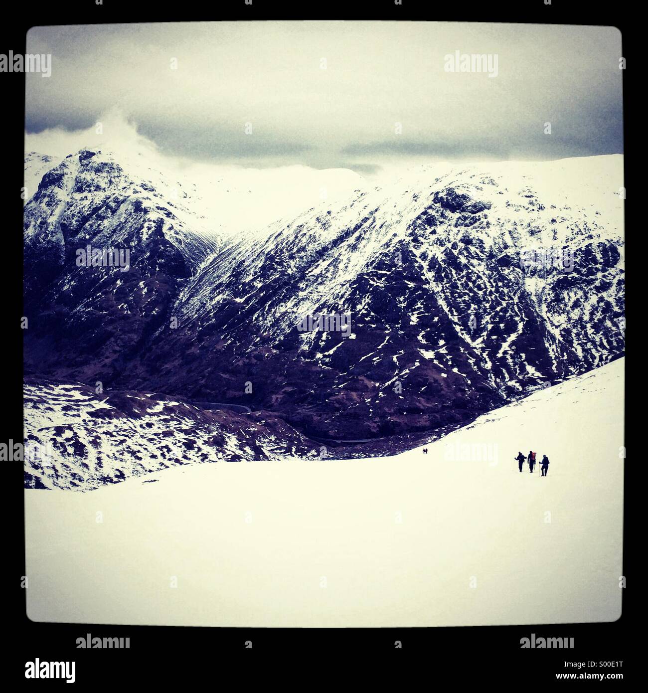 Three mountaineers descend a snow slope in Glencoe, Scotland, UK - Smartphone Captured Stock Image