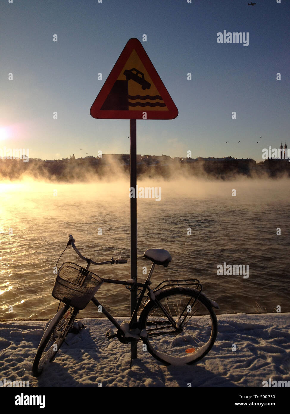 Bicycle leans against dock edge sign in central Stockholm with misty lake at dawn in background. - Smartphone Captured Stock Image