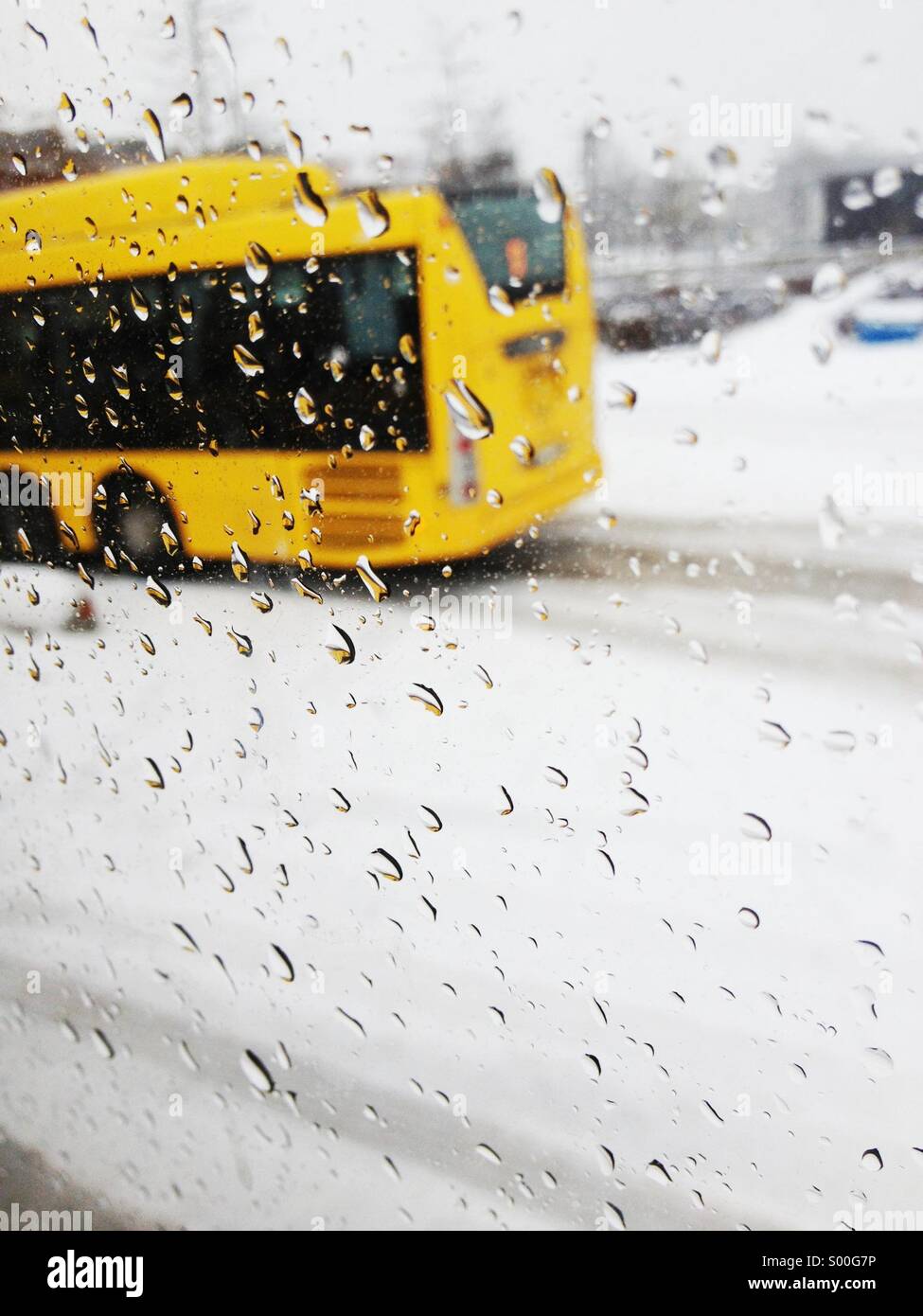 Yellow bus drives past with rain and wet snow on window in Uppsala, Sweden. Stock Photo