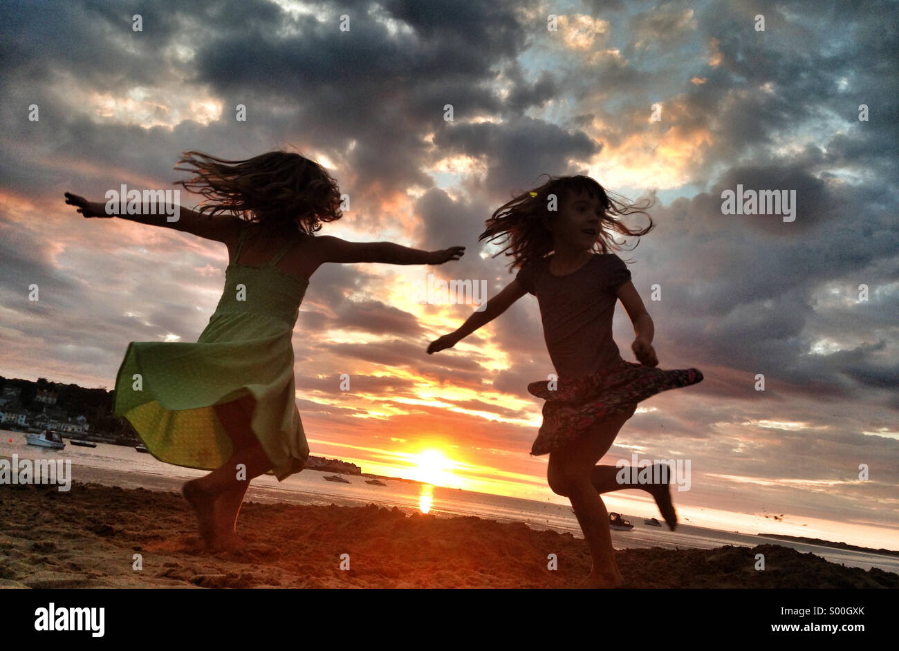 Girls whirl on the sand at sunset on the beach in devon, UK Stock Photo