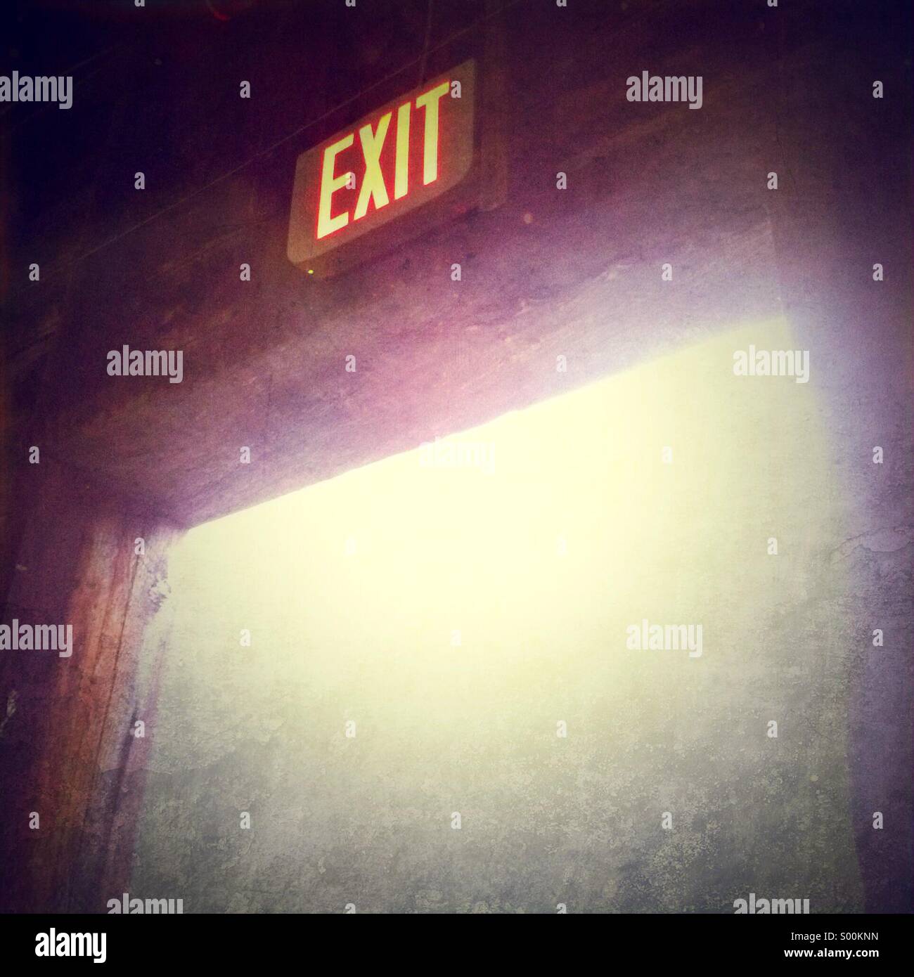 Exit sign above old doorway with bright foggy light streaming through from outside. - Smartphone Captured Stock Image