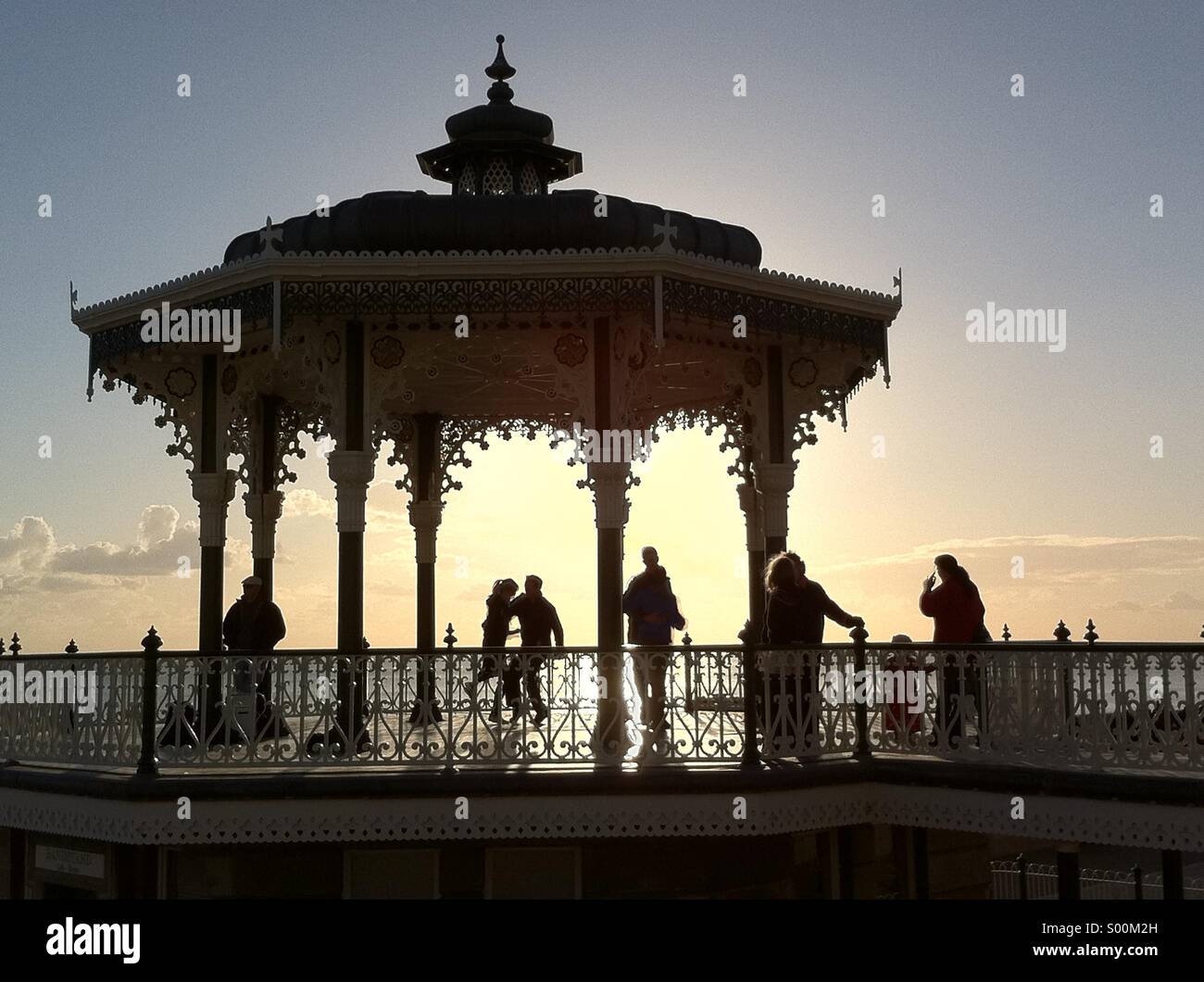 Silhouetted shapes of people dancing on Brighton's seafront bandstand at sunset, East Sussex, England Stock Photo
