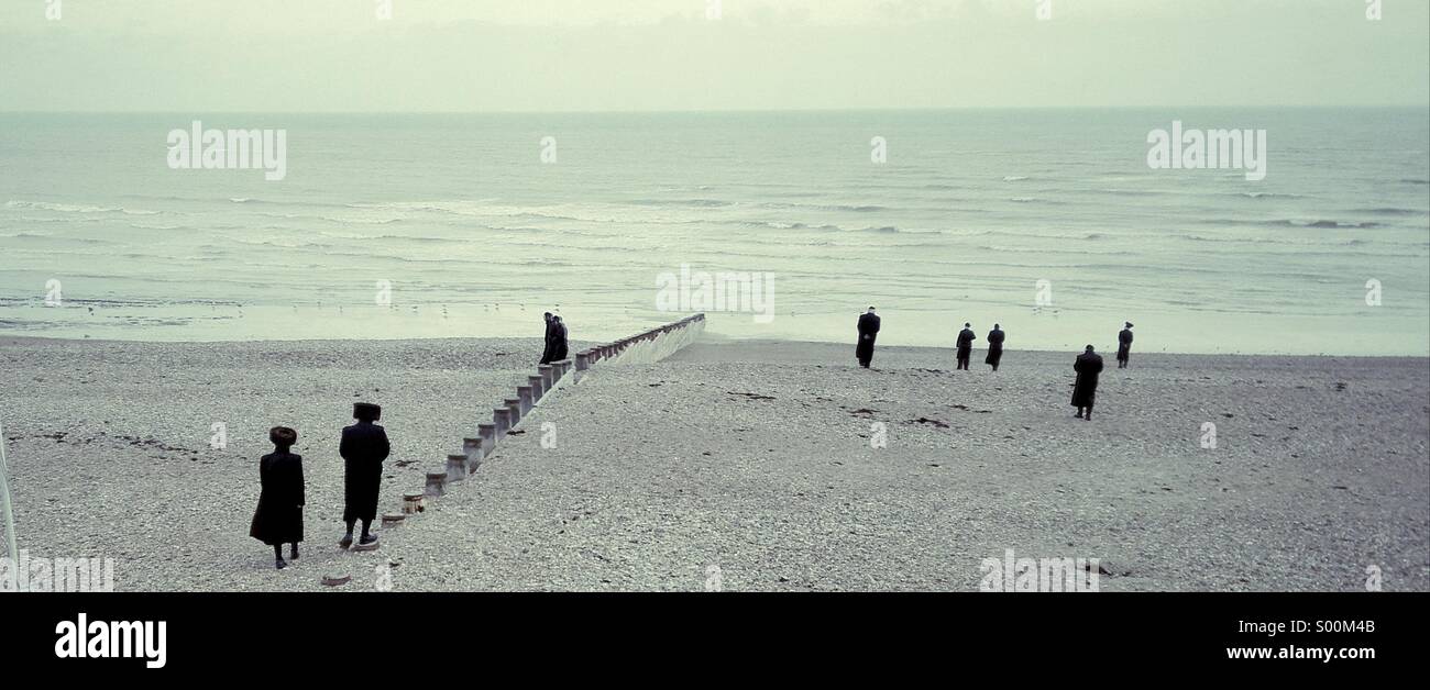 Orthodox Jews enjoying a stroll on a wintry Eastbourne beach, East Sussex, England. - Smartphone Captured Stock Image
