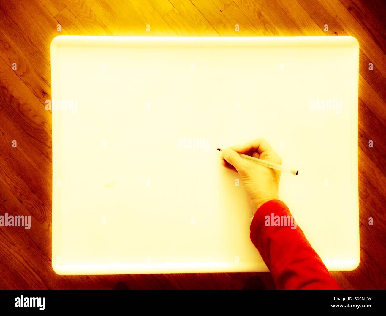 Hand holding pen to write on blank white sign, seen from above Stock Photo