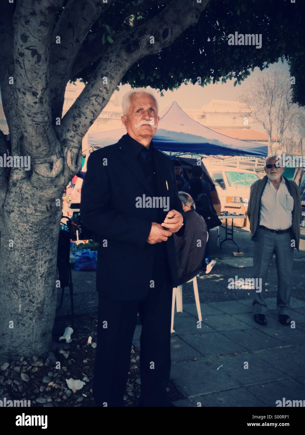 Old man with large white moustache stands proudly by a market Stock Photo